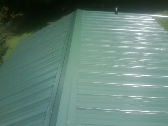 New green metal panels meeting at the ridge of a roof — Flat Roof Repair work by our crew in Cartwright