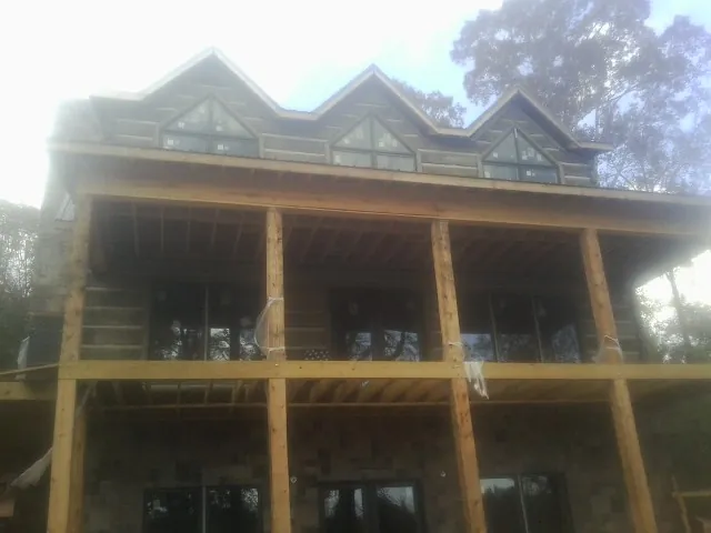Dormers and porch framing on a large log home under construction — Roof Coating work by our crew in Cartwright