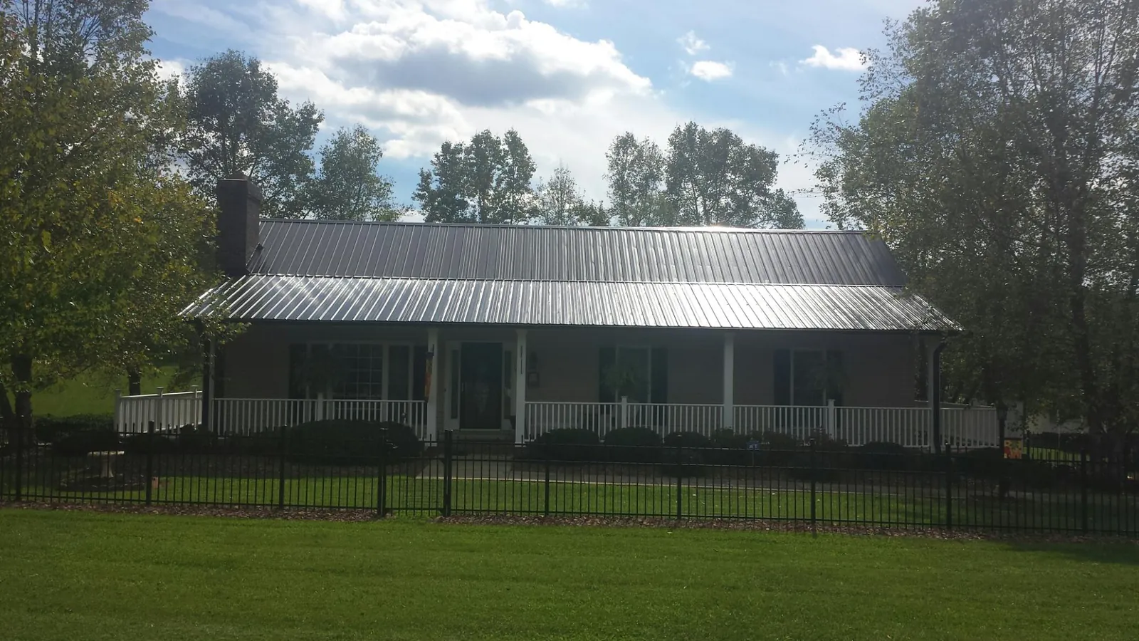 Gray metal roof on a brick ranch with a full width front porch — Gutter Guard Installation work by our crew in Cartwright